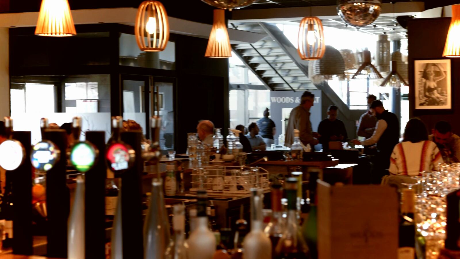 Le bar du WOODS en plein service, sous les suspensions en bois, à Bourgoin-Jallieu