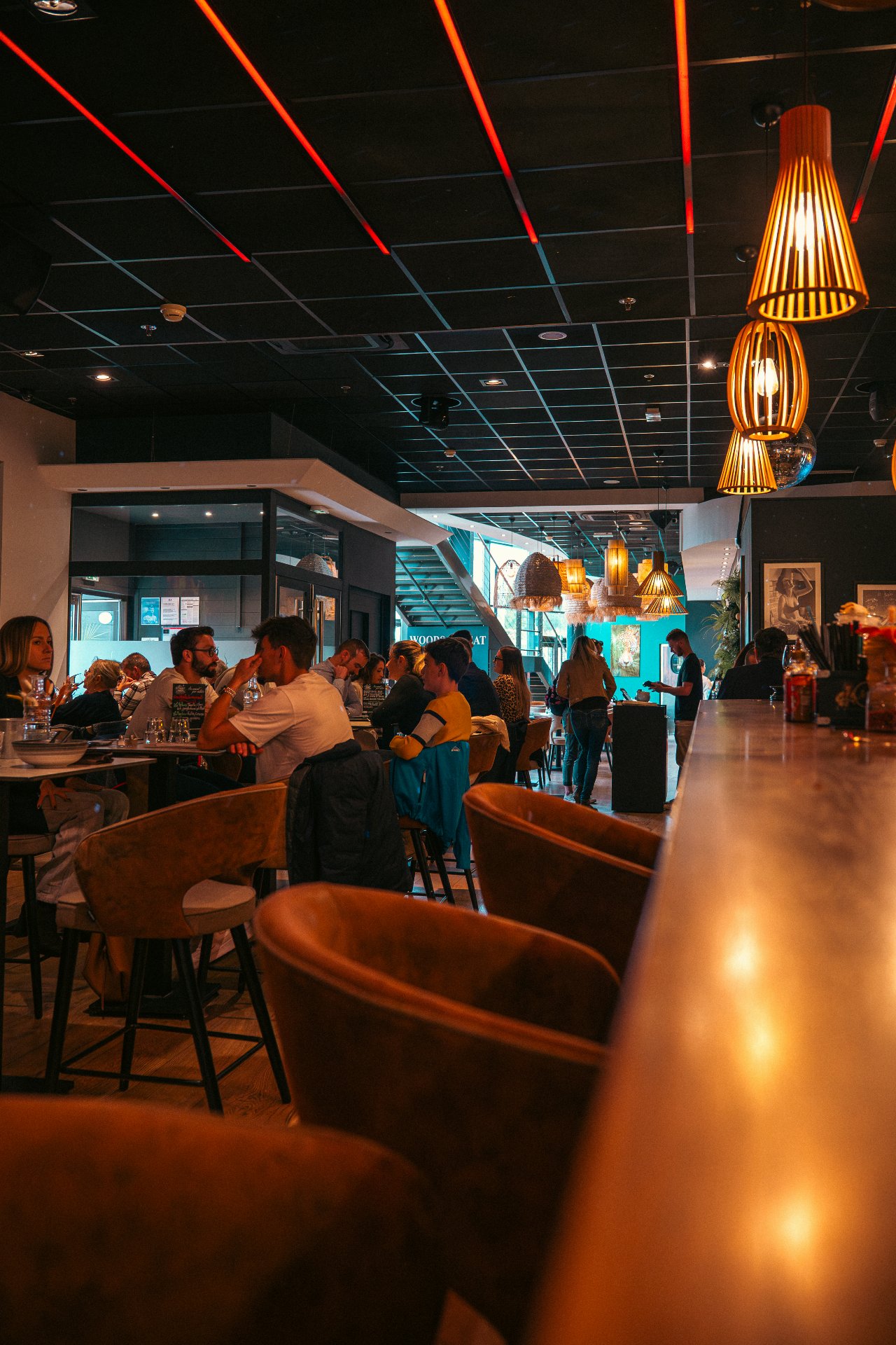 Salle du restaurant WOODS à Bourgoin-Jallieu avec décoration végétale, murs verts et lumières tamisées ambiance chic.